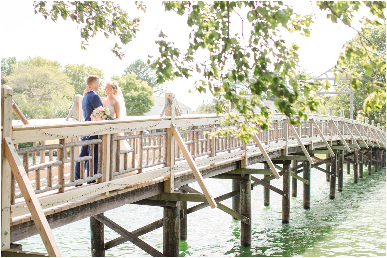 Bride and groom kissing on bridge at Divine Park in Spring Lake