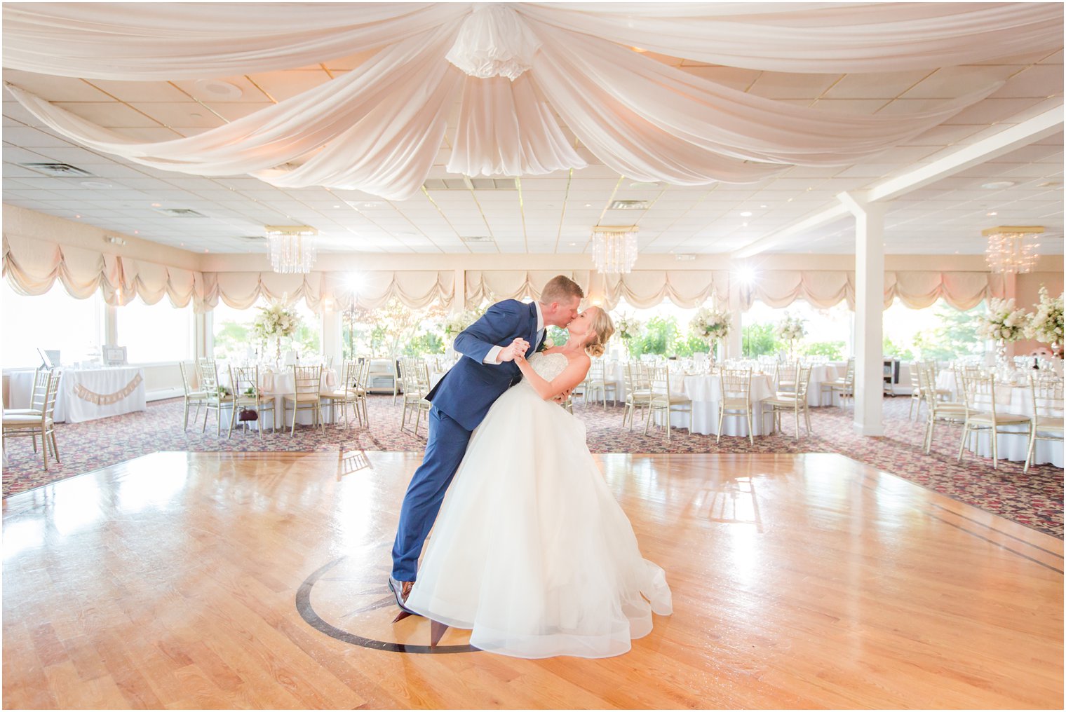 bride and groom kissing in empty ballroom at Crystal Point Yacht Club