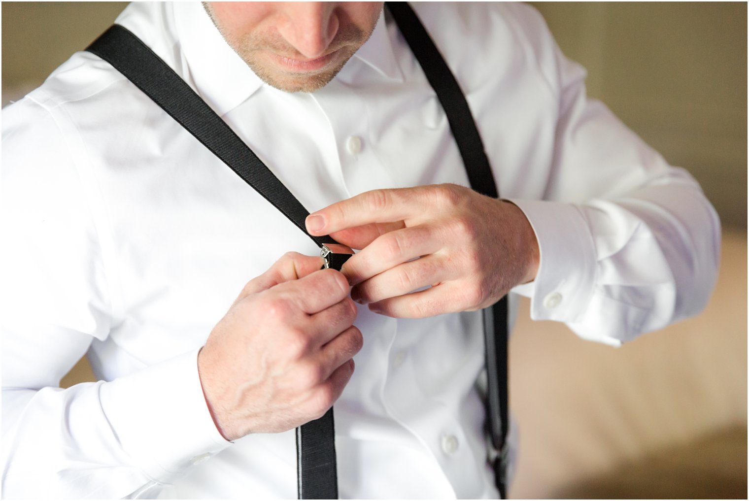 groom putting on suspenders