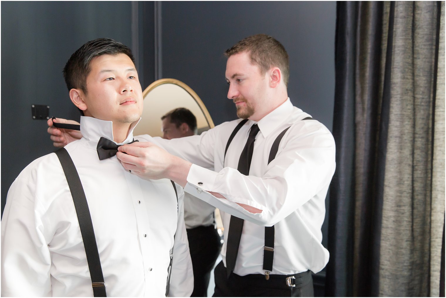 best man helping groom get dressed