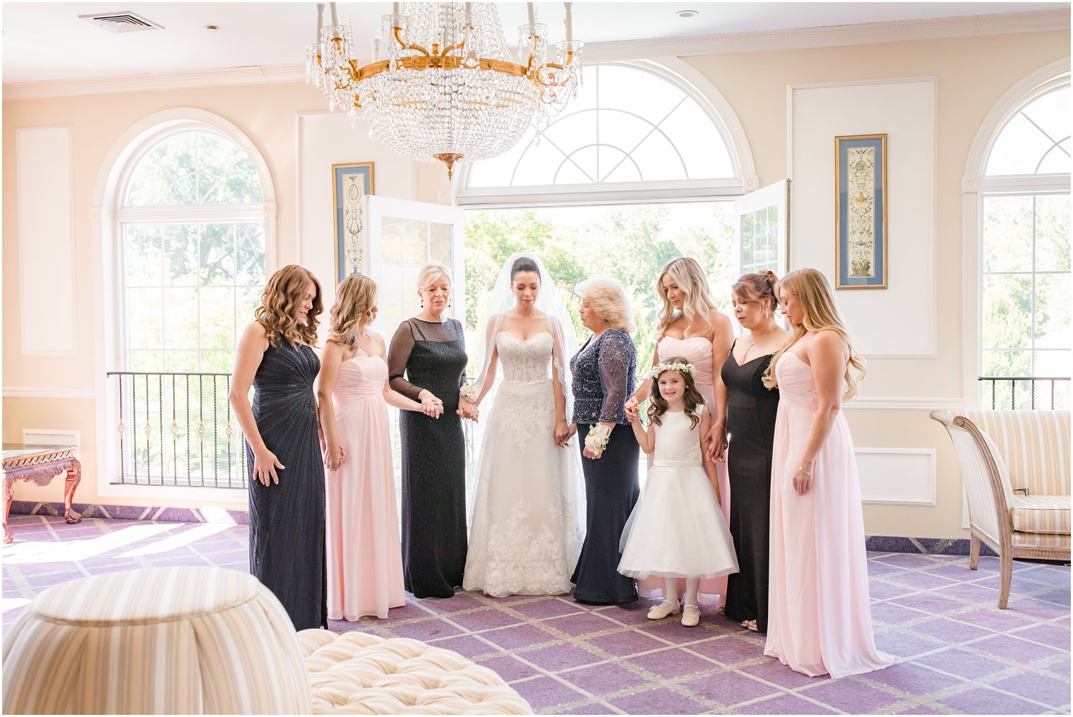 Bride praying with her family and bridesmaids