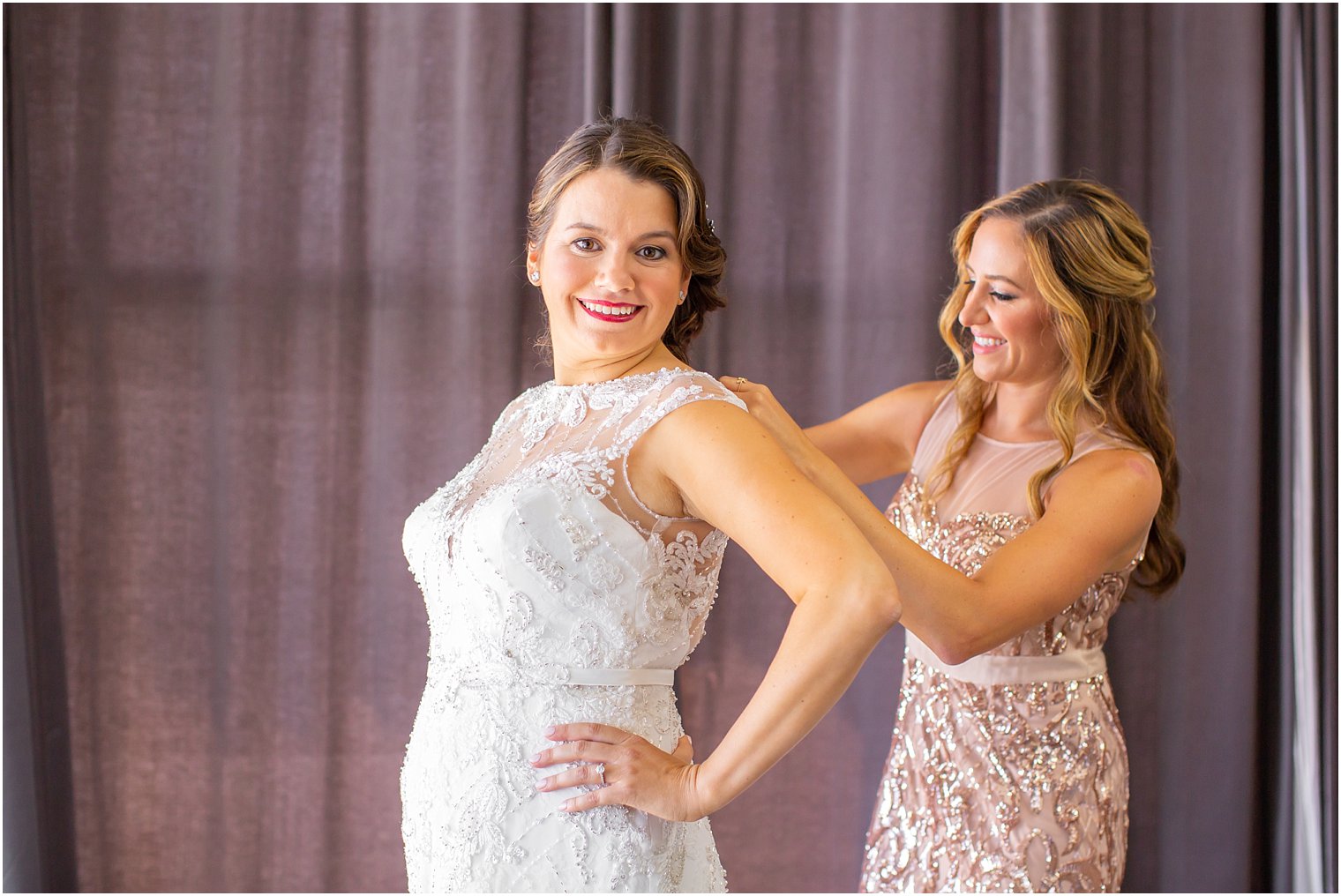 bridesmaid helping bride into lace Maggie Sottero wedding gown