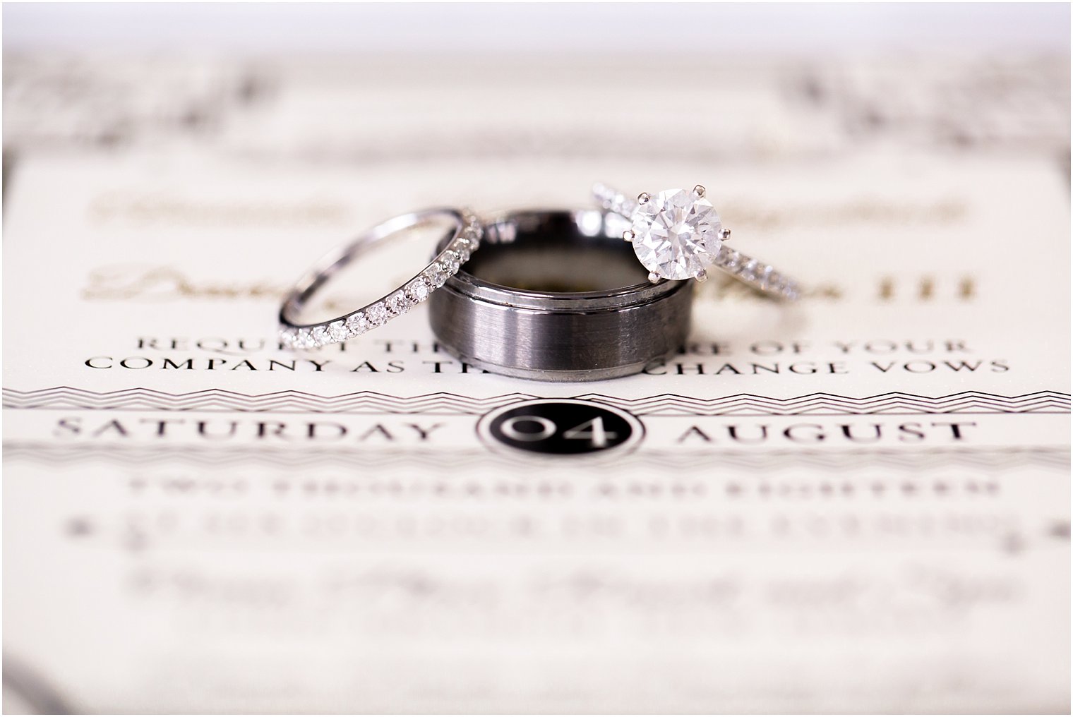 wedding bands sitting on black and ivory invitation by Perfectly Invited