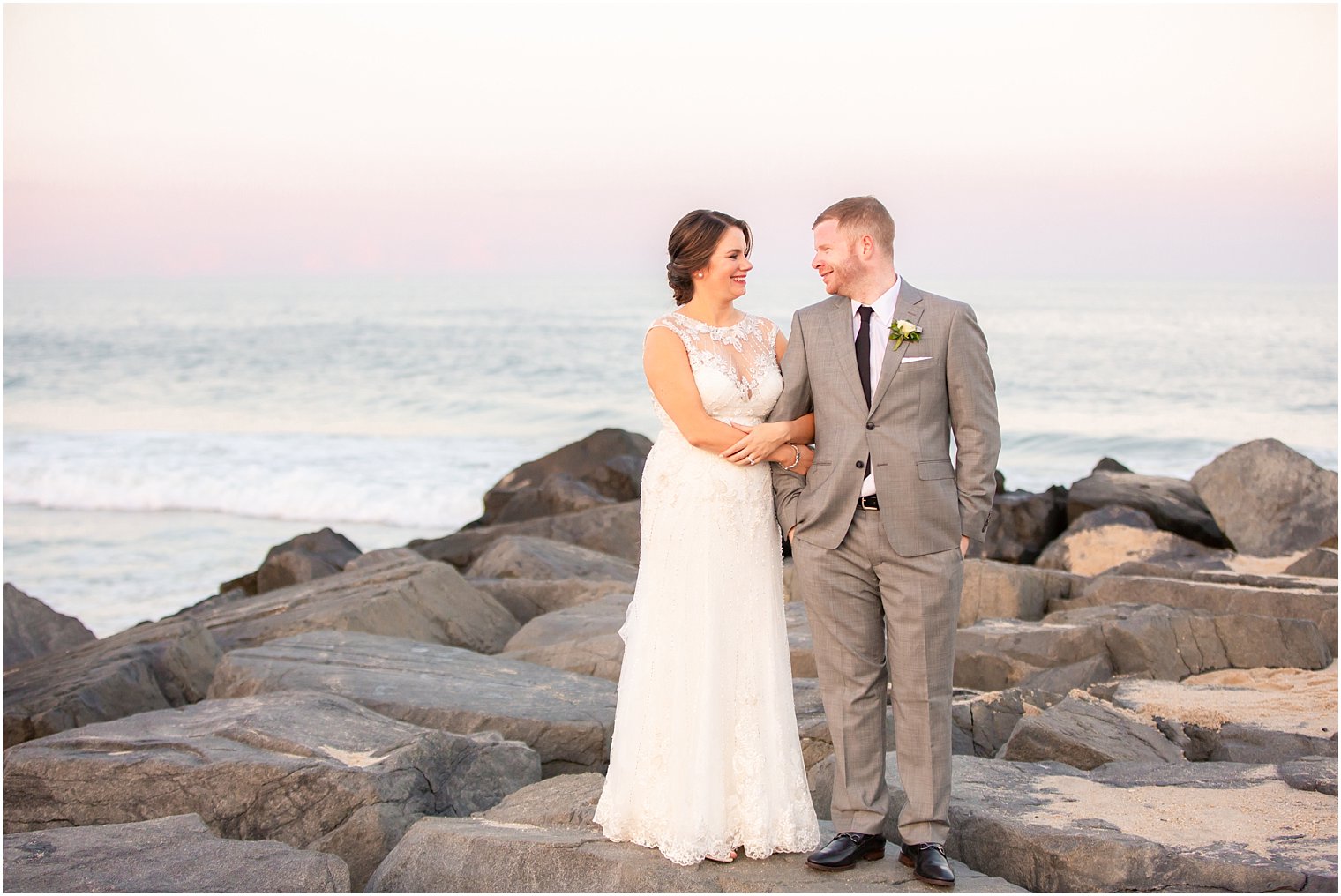 bride and groom posing on rocks at beach photographed by Long Branch NJ wedding photographer Idalia Photography