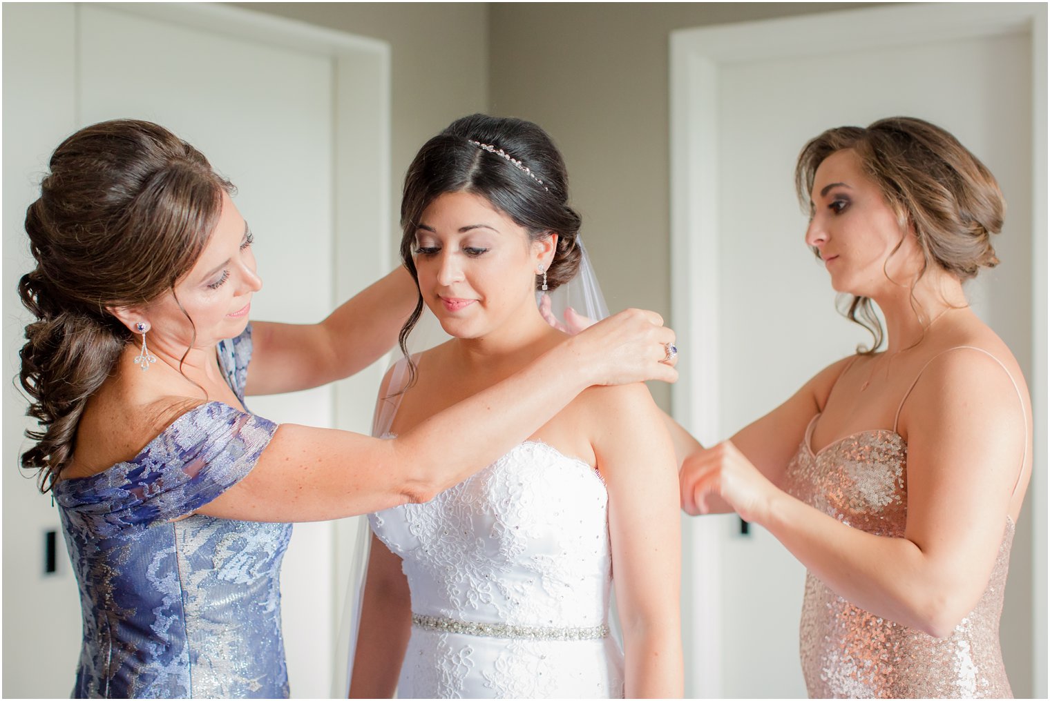 mother and bridesmaid help bride with veil on wedding day photographed by Idalia Photography