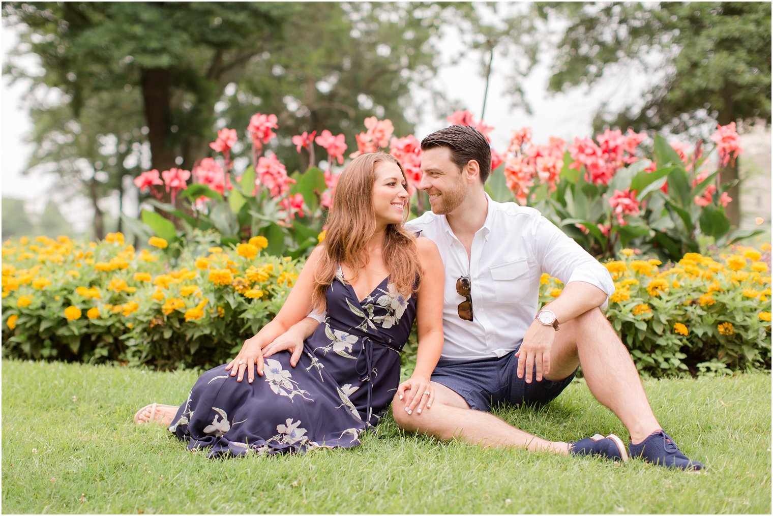 engaged couple sits in front of garden flowers during Spring Lake NJ Engagement session