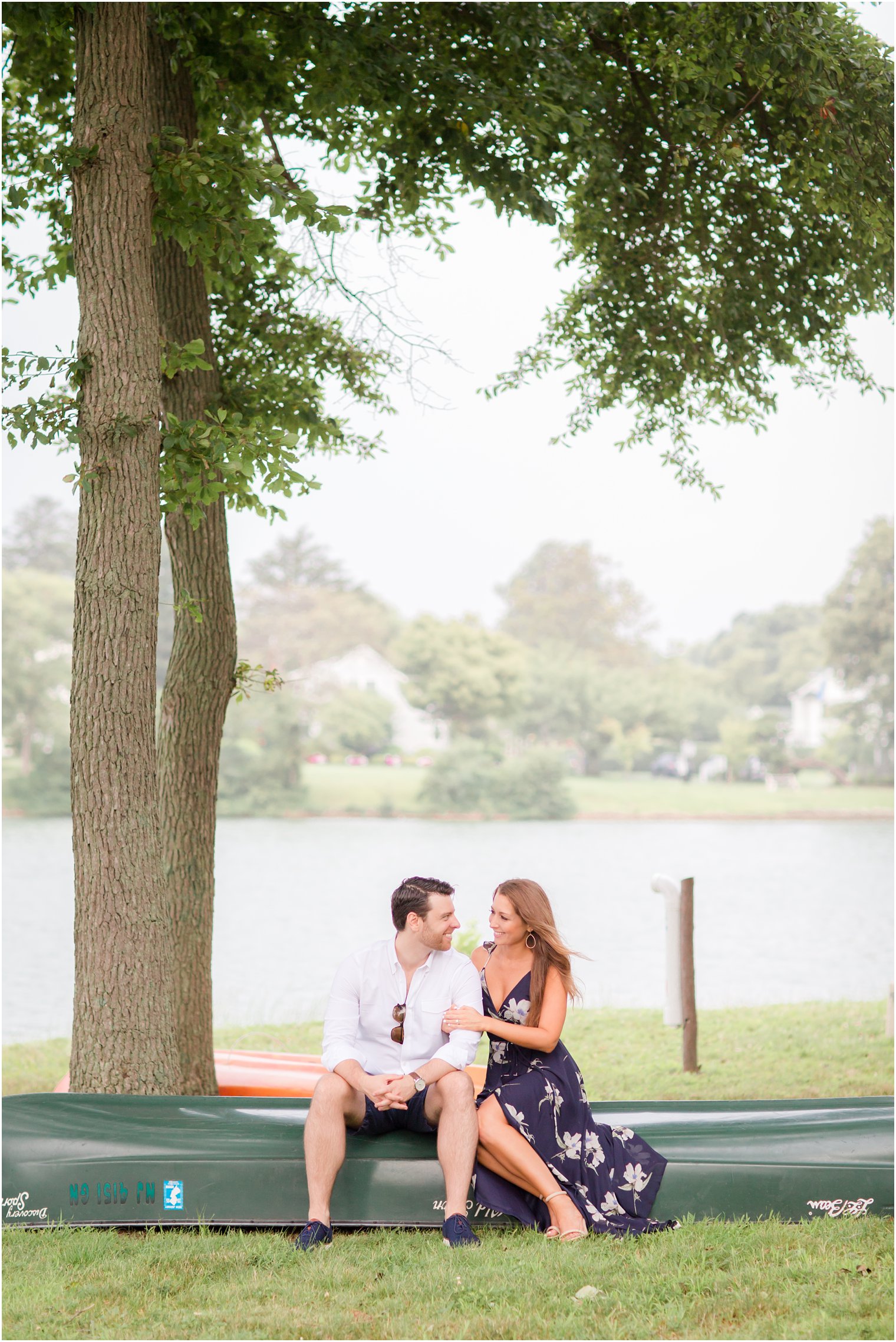 engaged couple sits on canoe during Spring Lake NJ Engagement session with Idalia Photography