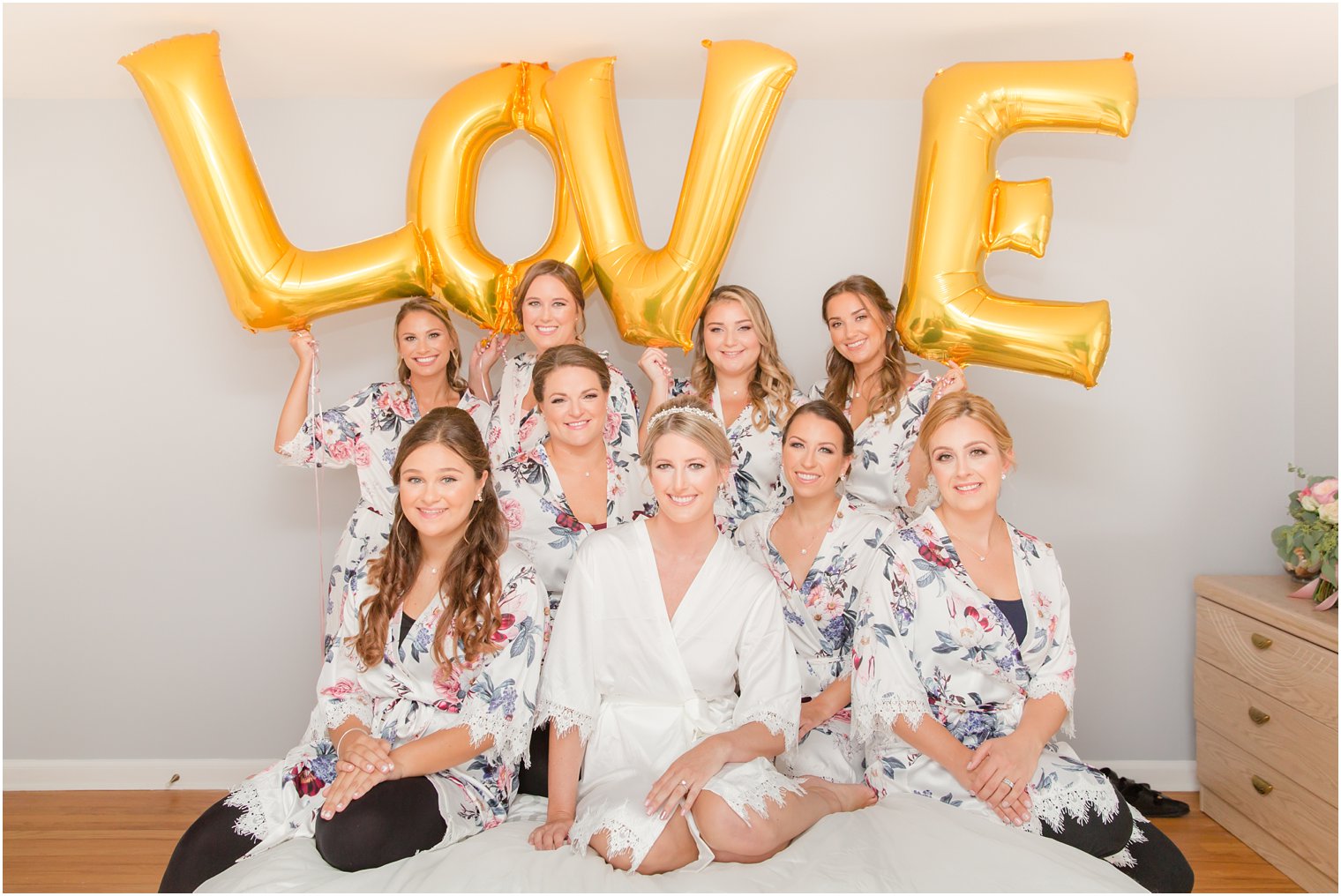 bride and bridesmaids in white robes with LOVE balloons 