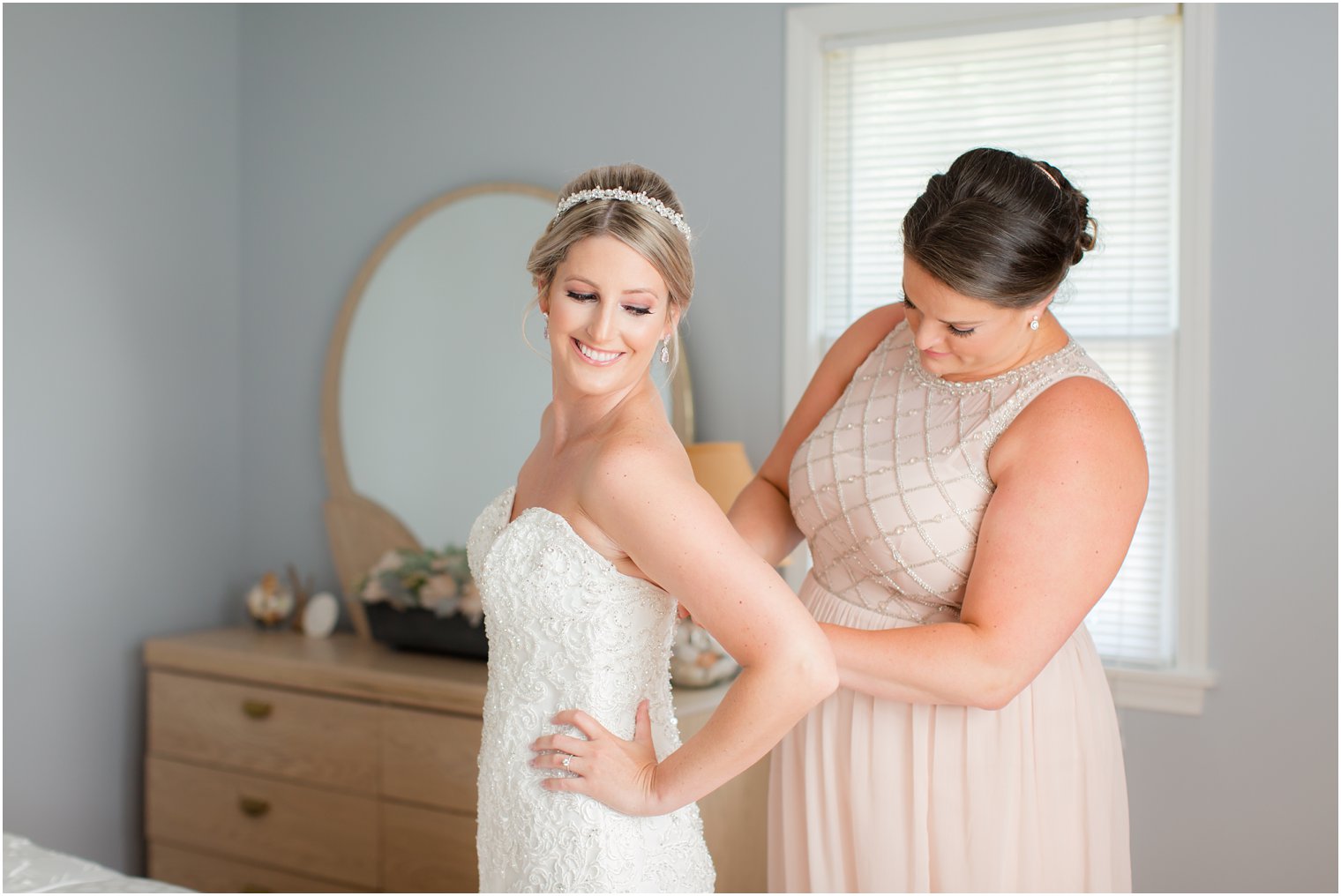 bride getting into wedding dress with bridesmaid before Palace at Somerset Park wedding