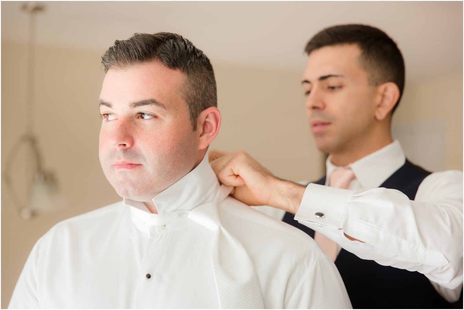 groomsman helps groom with tie on wedding day before Palace at Somerset Park wedding