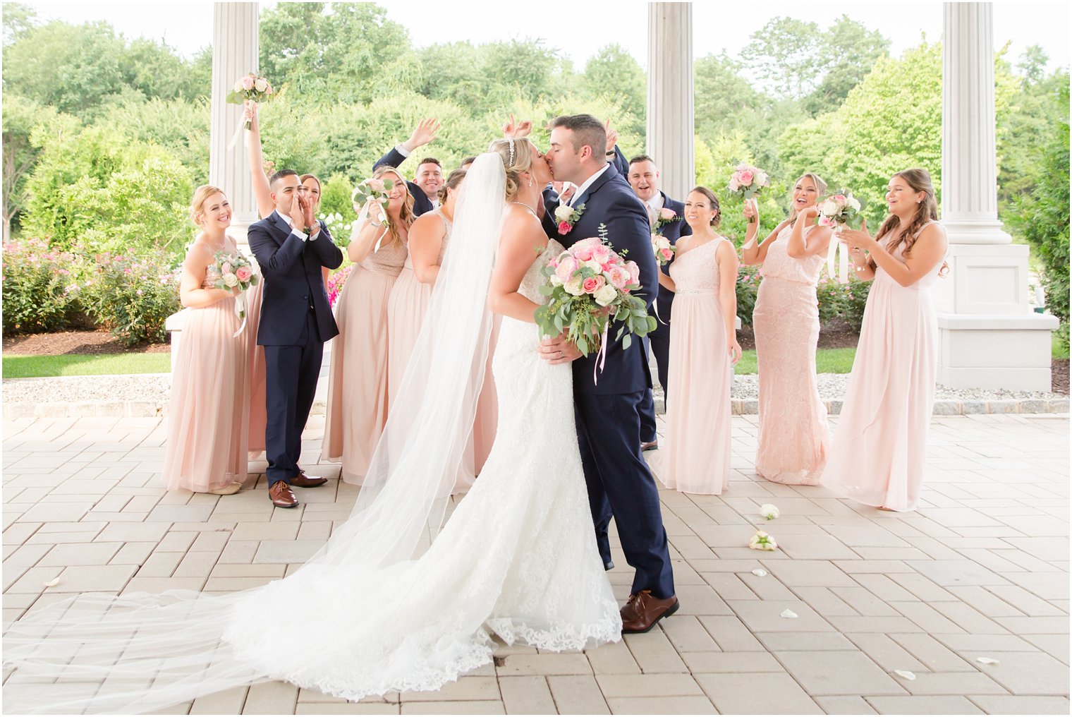 bride and groom kiss in front of wedding party at Palace at Somerset Park in Somerset NJ photographed by Idalia Photography