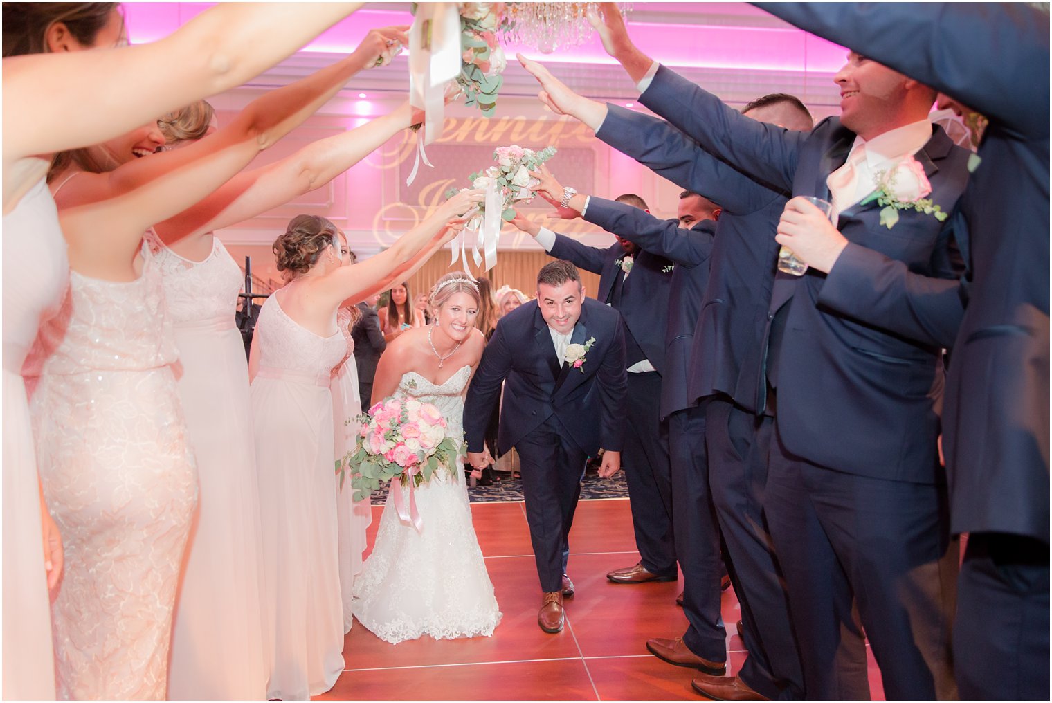 bride and groom enter reception under archway created by wedding party at the Palace at Somerset Park