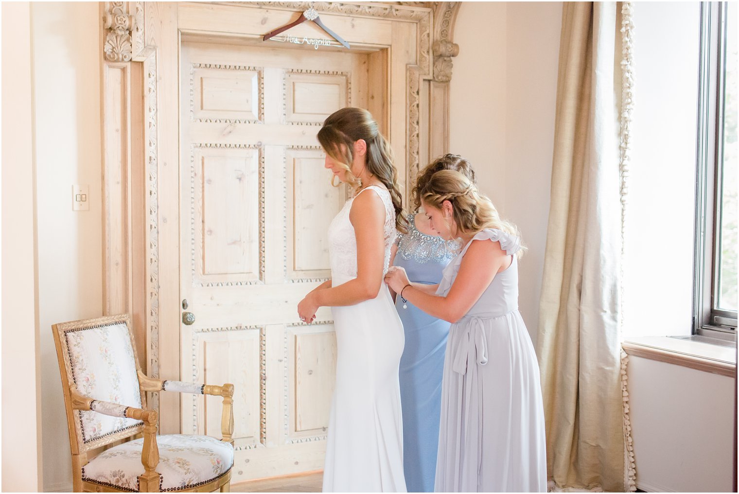 bride getting into wedding gown with help of bridesmaid and mother at Jasna Polana
