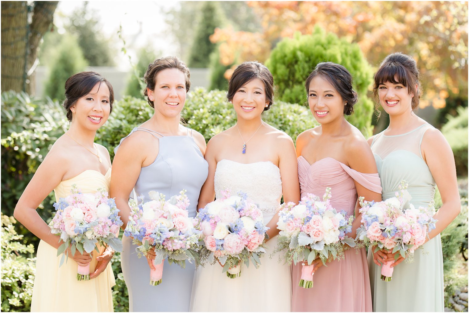 bride with bridesmaids in pastel gowns from David's Bridal with bouquets from Secret Garden