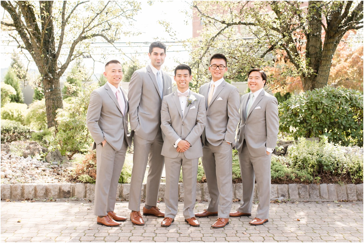 groom poses with groomsmen in light grey suits from Men's Wearhouse at The Bethwood