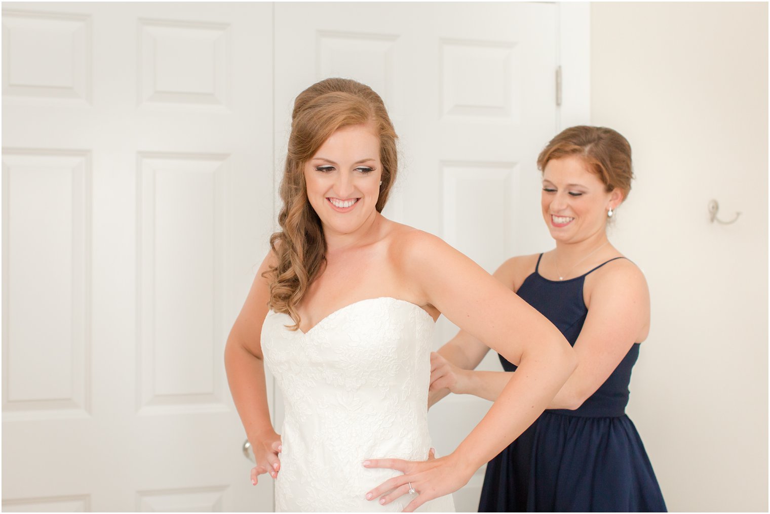 bridesmaid helps bride into wedding dress photographed by Idalia Photography