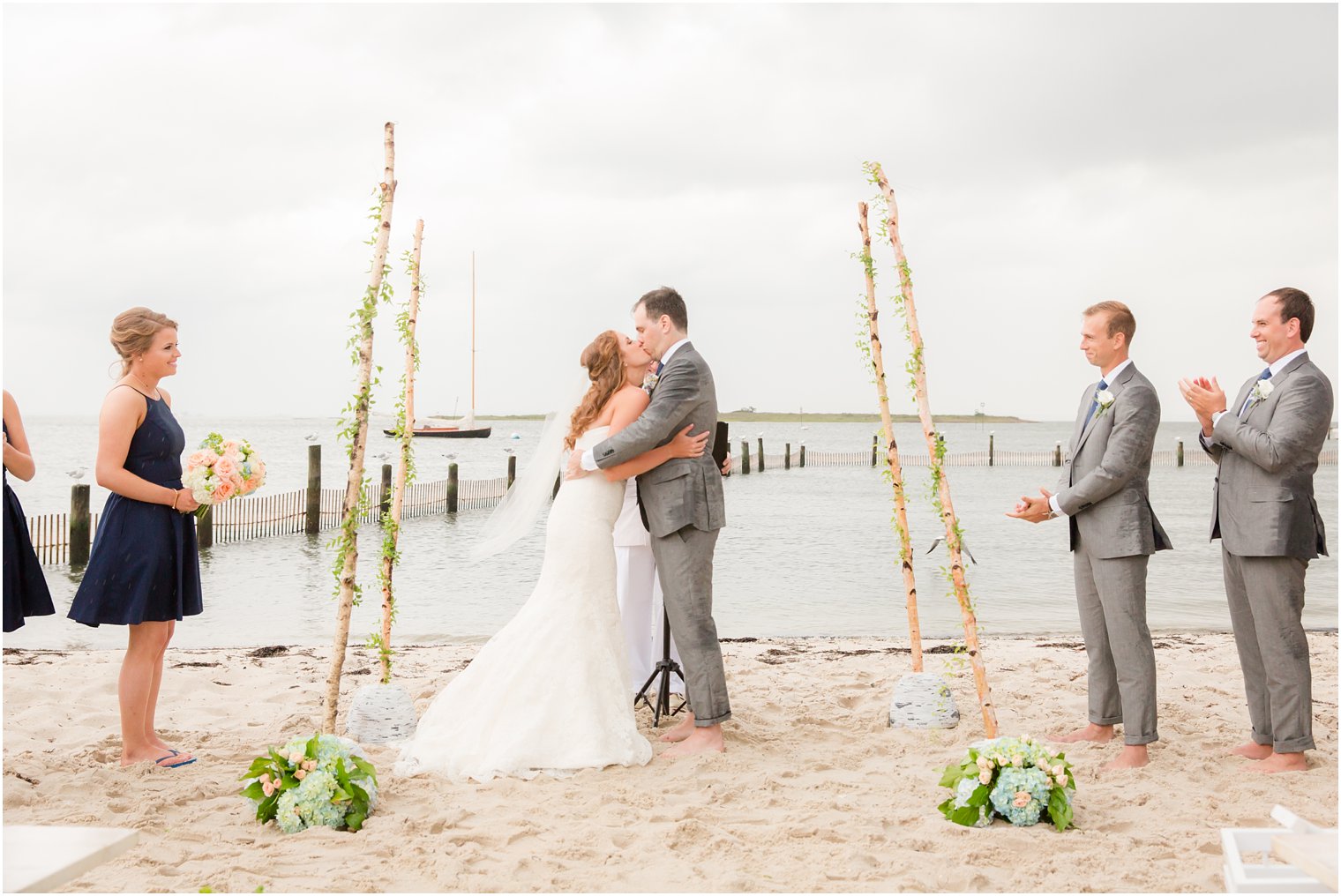 bride and groom celebrate first kiss on Brant Beach Yacht Club beach photographed by Idalia Photography