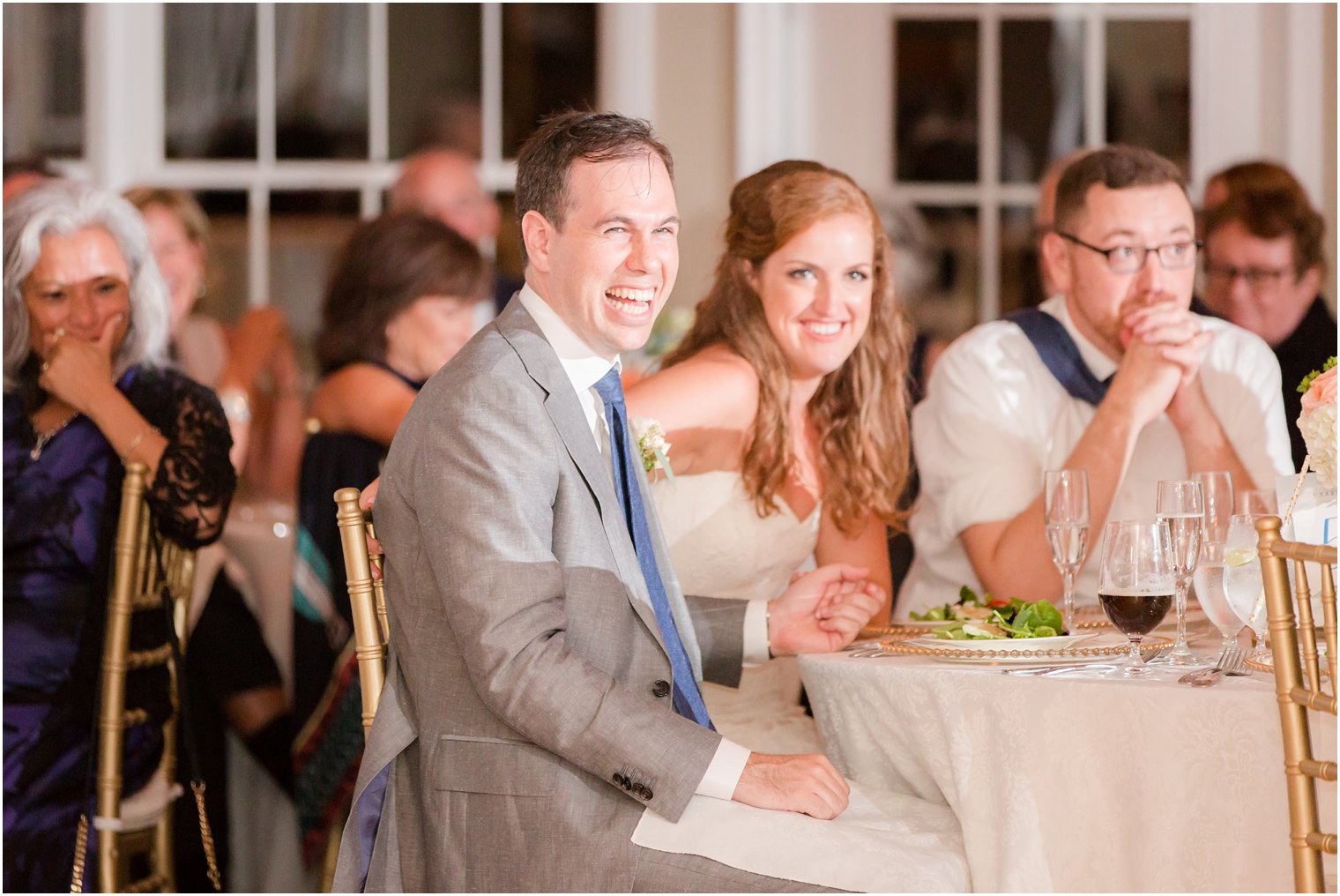 groom laughs during wedding toasts at Brant Beach Yacht Club photographed by Idalia Photography