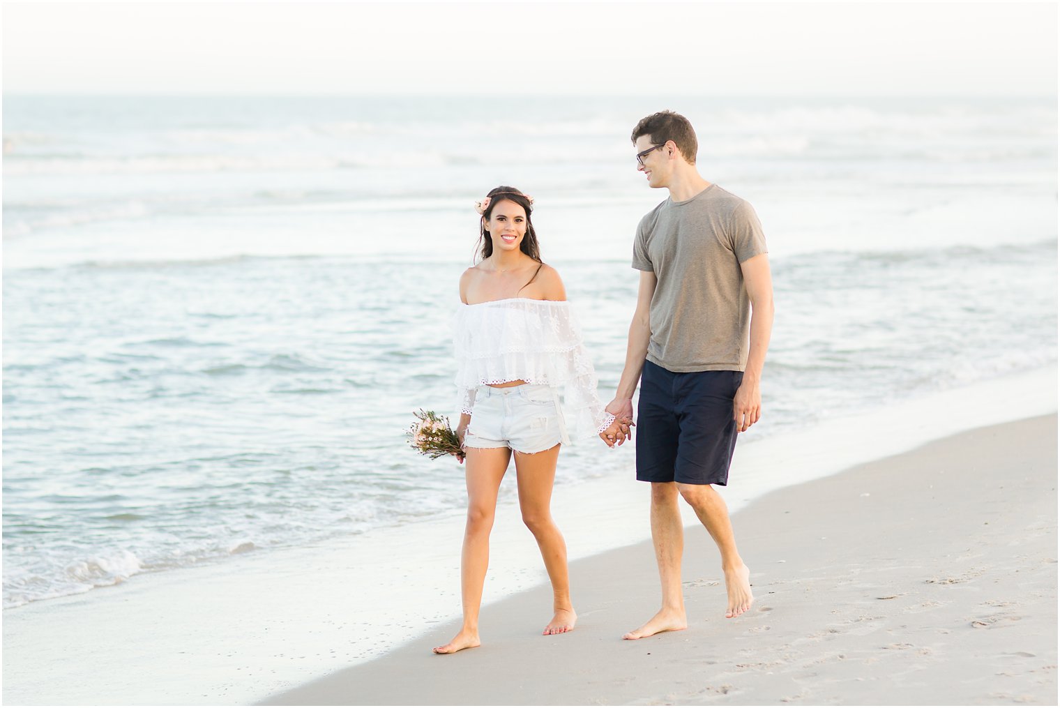 bride and groom walk along beach during Long Beach Island engagement session with Idalia Photography
