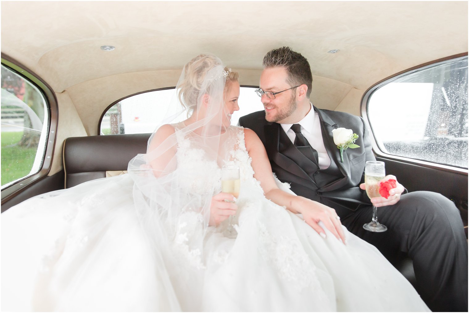 bride and groom share champagne after wedding ceremony in classic car