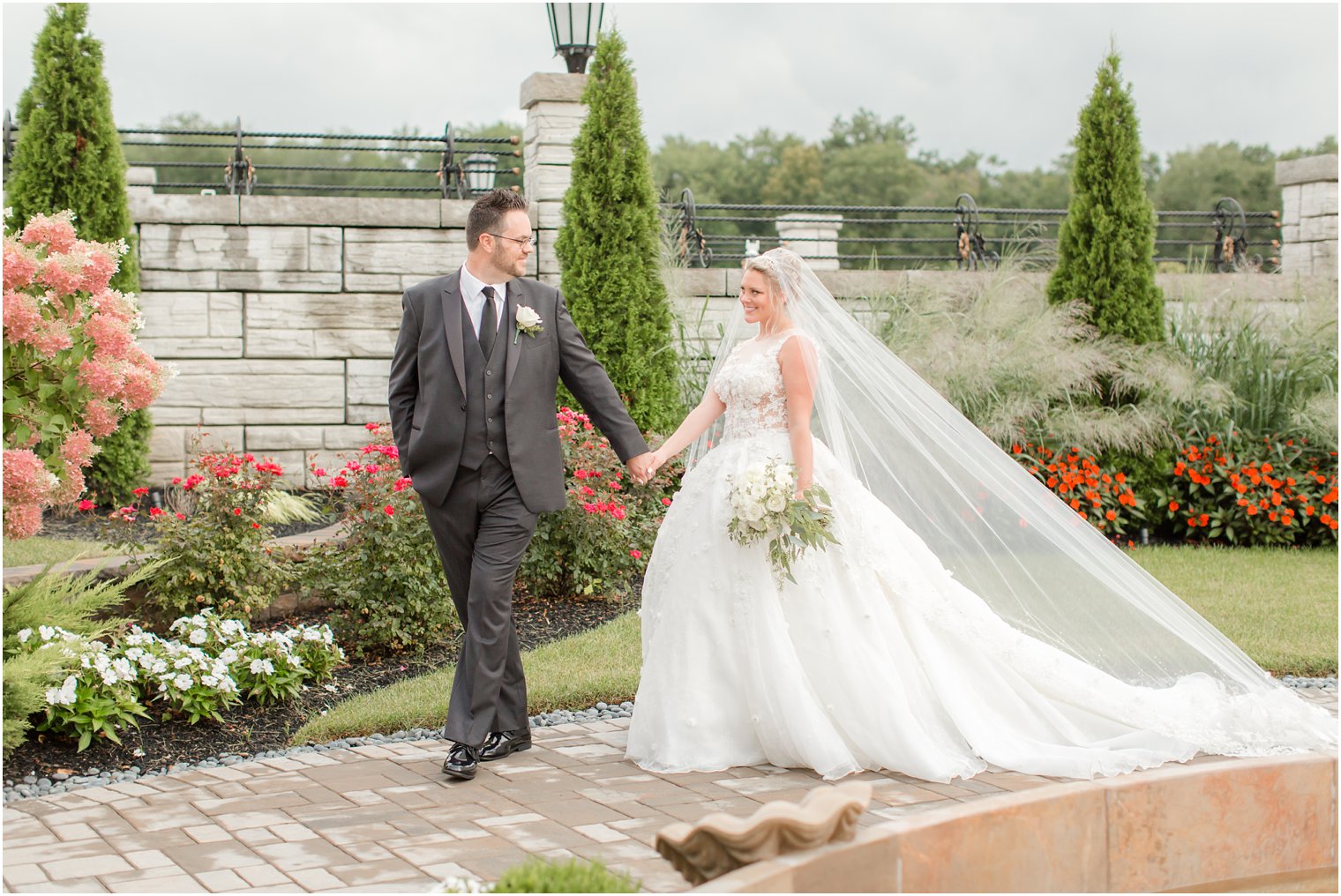 bride and groom walk through gardens at Legacy Castle during portraits with Idalia Photography