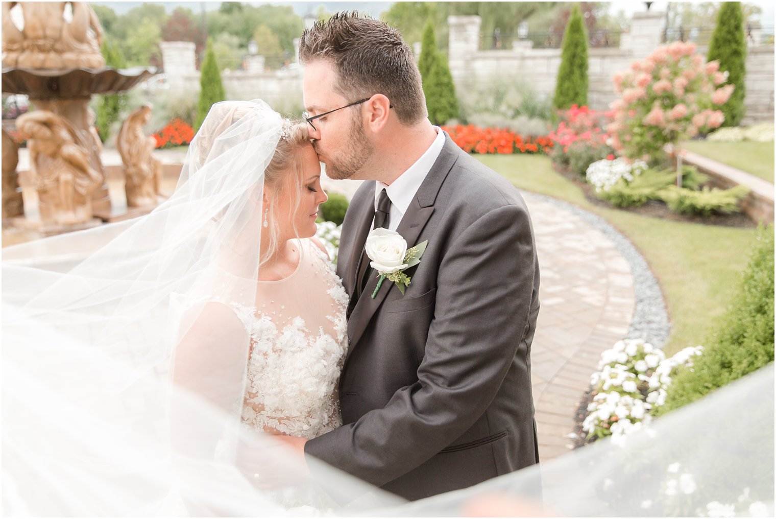 groom kisses bride on forehead during veil shot at Legacy Castle by Idalia Photography