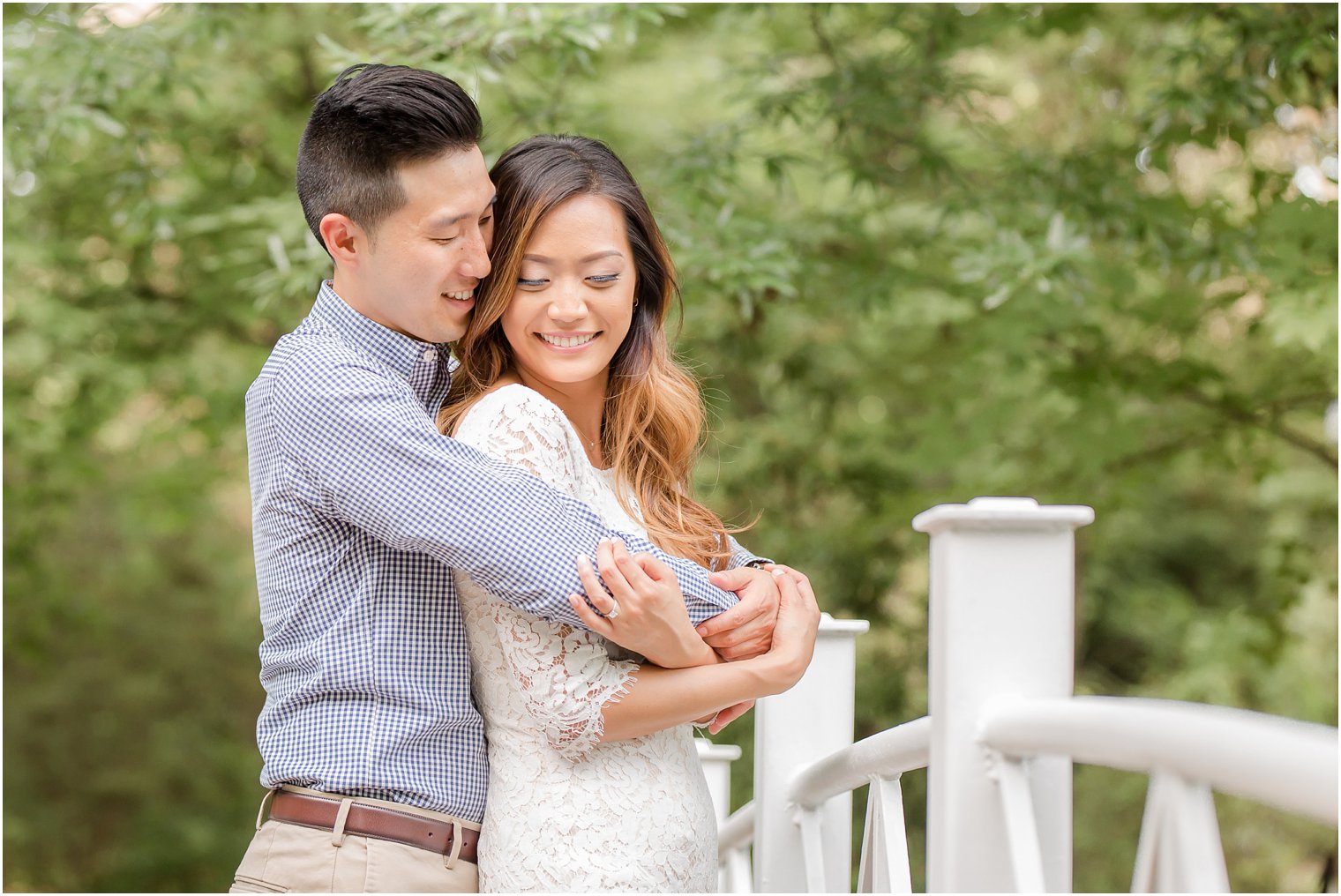 engaged couple poses on bridge at Sayen House and Gardens during engagement session