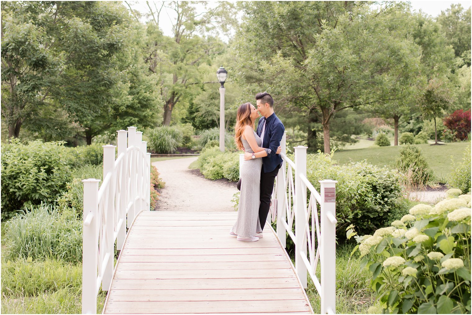 couple relaxes on bridge during engagement session at Sayen House and Gardens with Idalia Photography