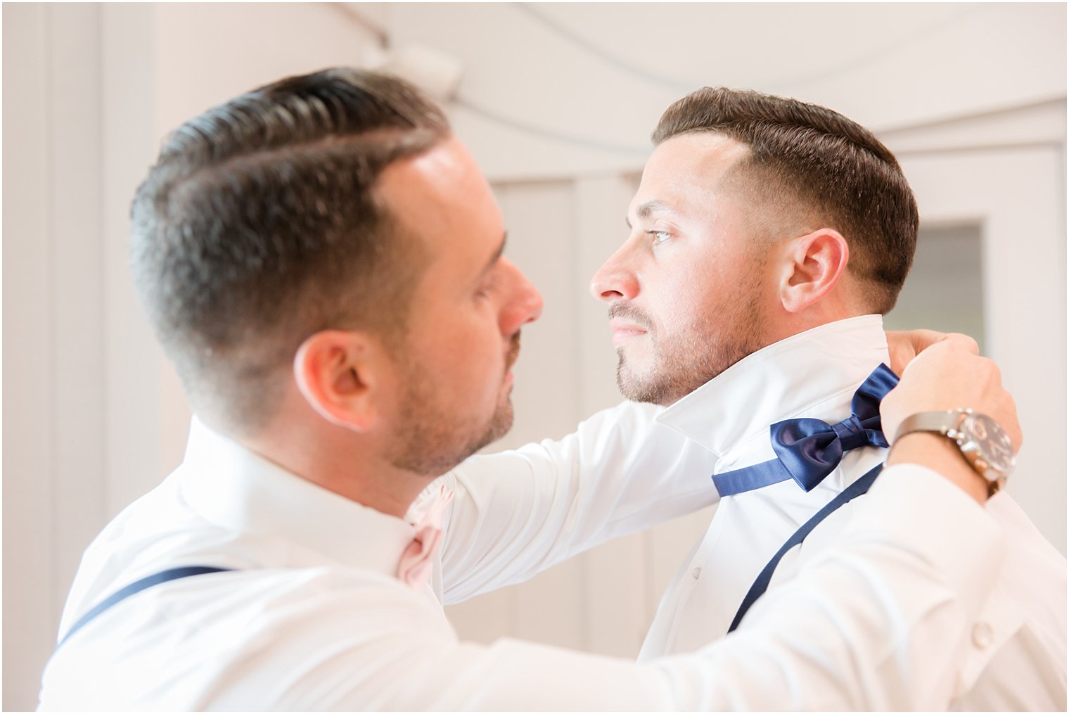 groomsman helps groom with tie before wedding at Windows on the Water at Frogbridge
