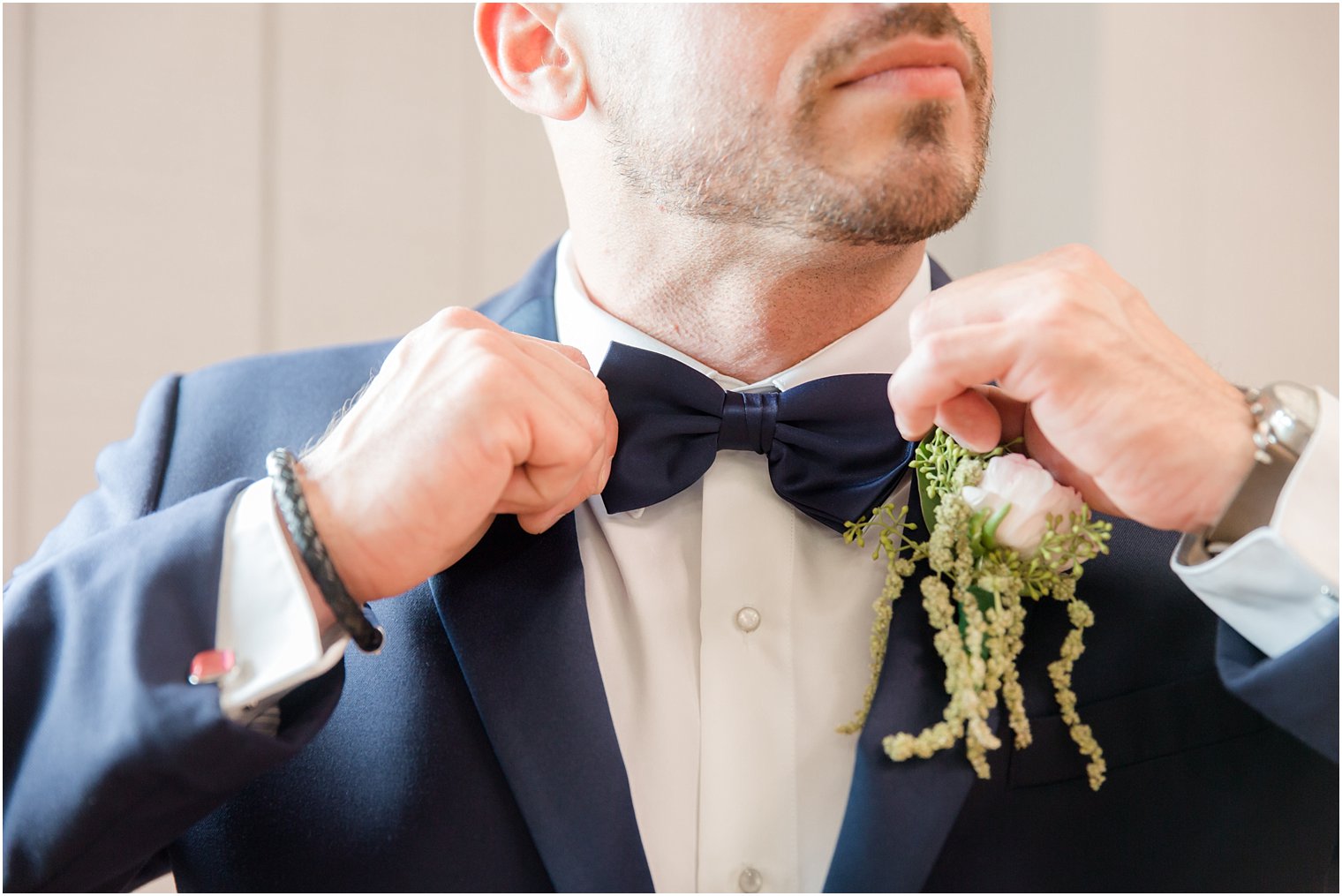 groom fixes navy blue tie for Windows on the Water at Frogbridge wedding day