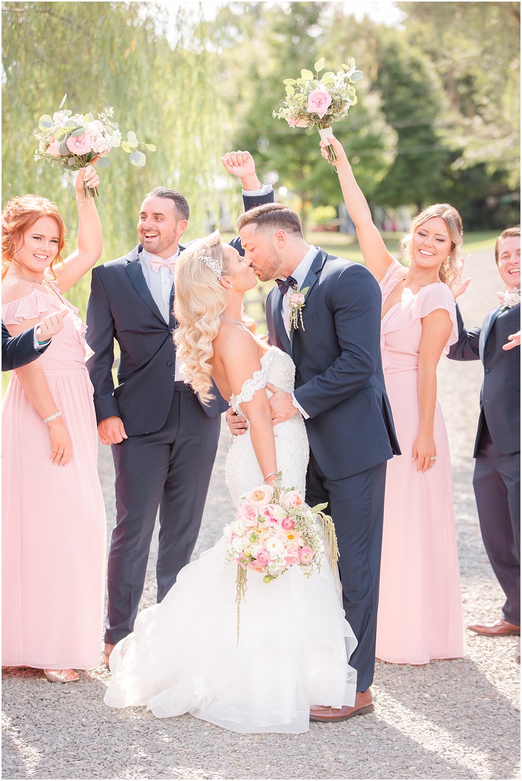 bride and groom kiss at Windows on the Water at Frogbridge with wedding party celebrating