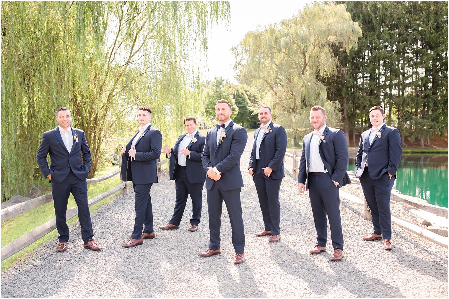 groom with groomsmen in navy suits by pond at Windows on the Water at Frogbridge