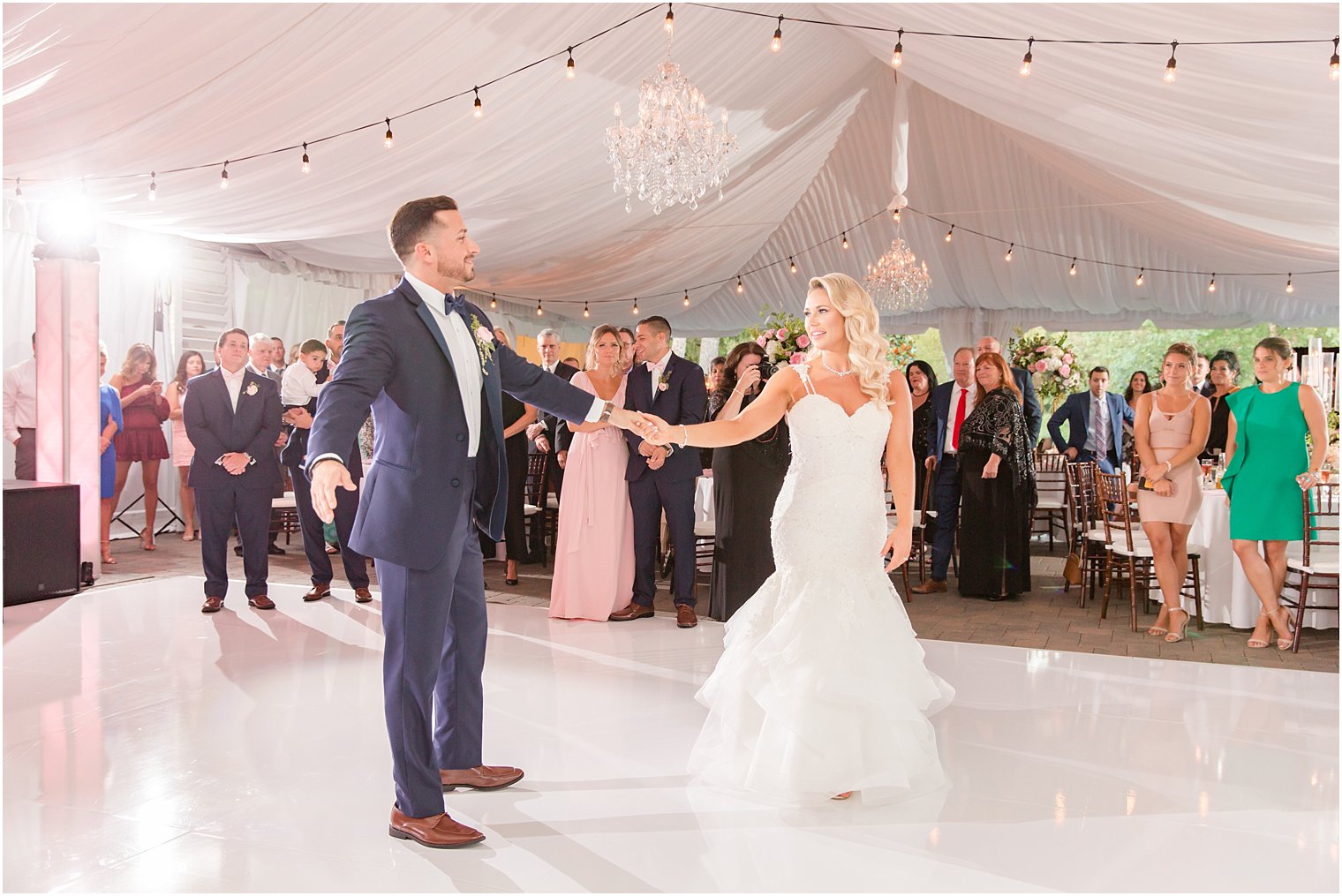 bride and groom dance under lights in tented reception at Windows on the Water at Frogbridge