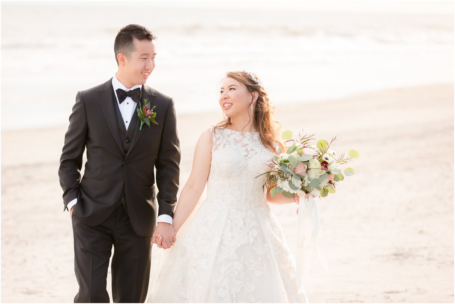 Wedding photo of groom in black tie and bride wearing lace A-line dress by Oleg Cassini