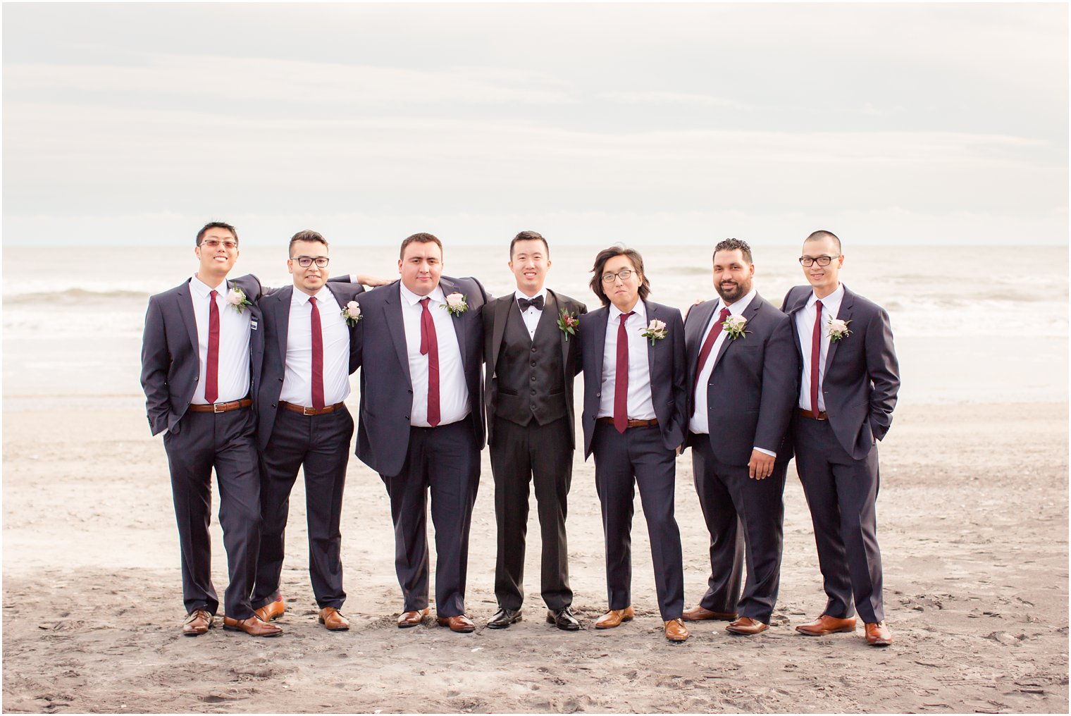 Groomsmen wearing navy suits and burgundy ties for fall wedding