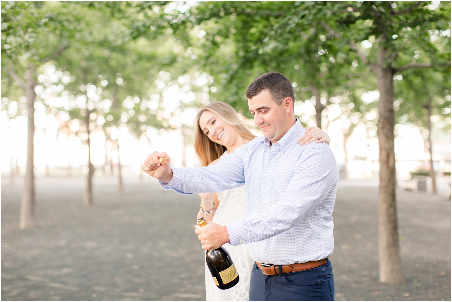 couple pops champagne during engagement portraits in Hoboken NJ with Idalia Photography