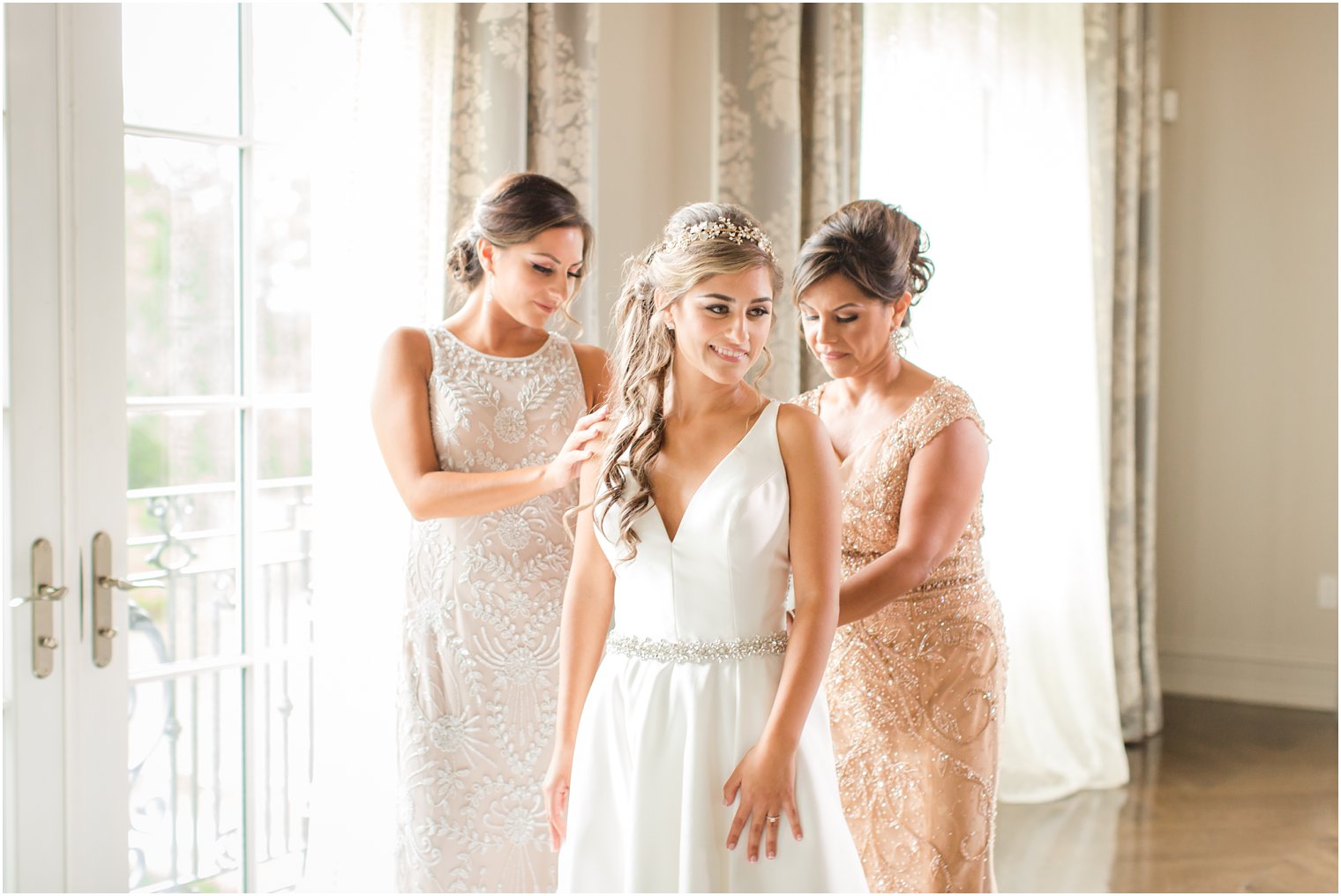 Bride's mother and sister helping her get dressed on her wedding day