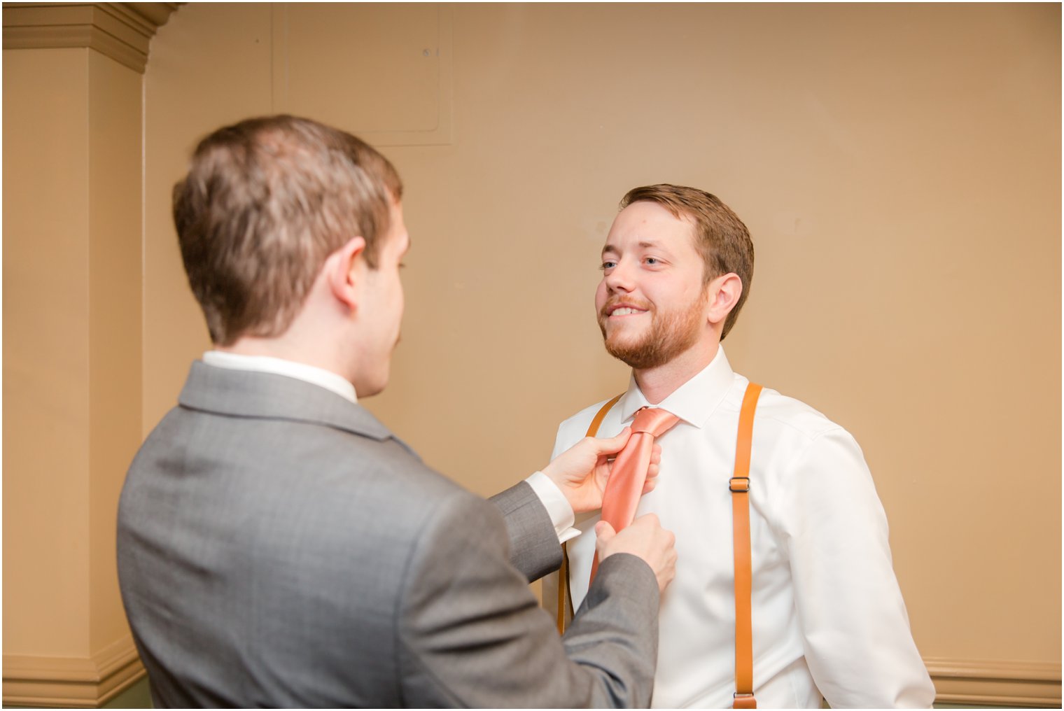 groomsman helps groom prepare for Olde Mill Inn wedding day by Idalia Photography