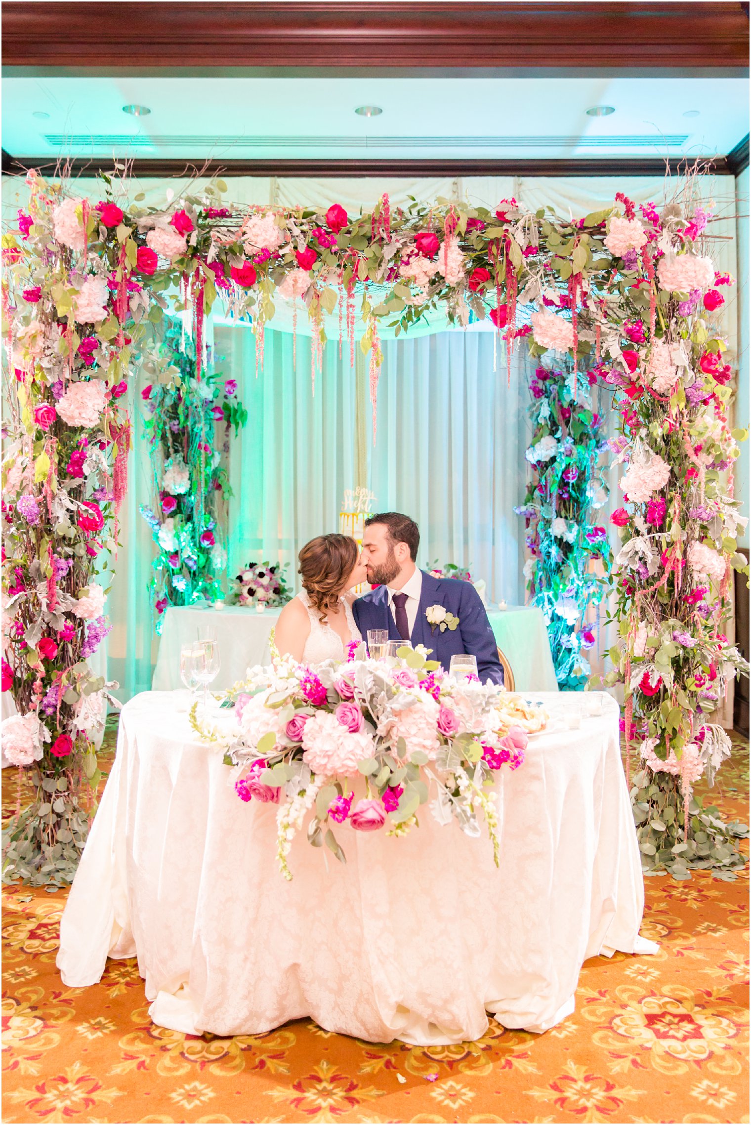 bride and groom under floral sweetheart table