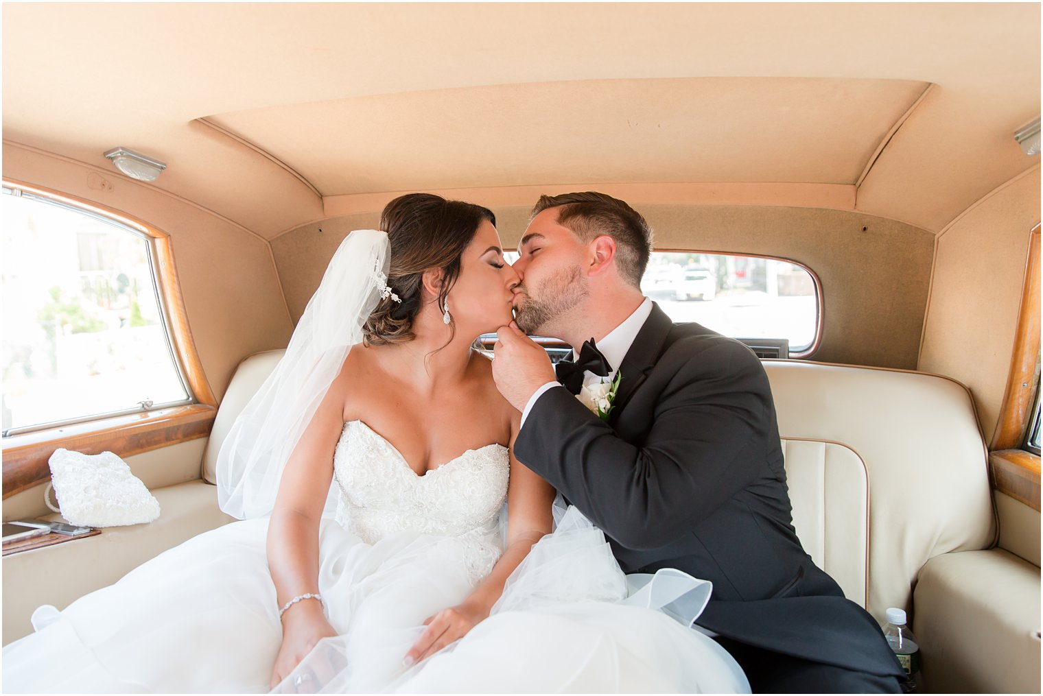 bride and groom kissing in the backseat of an antique car