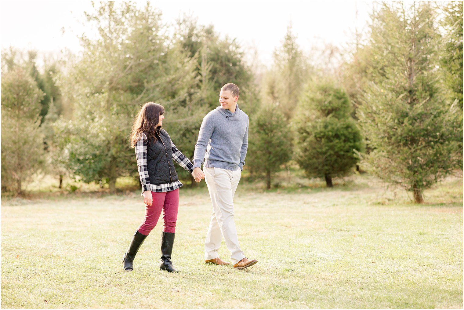 candid photos of engaged couple holding hands and walking on a tree farm