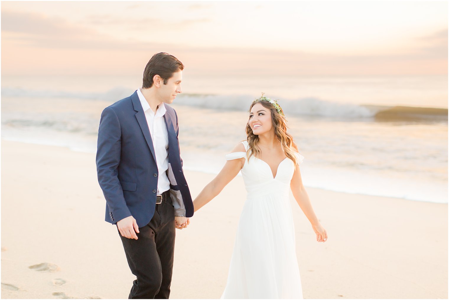 engaged couple walking on the beach at sunrise