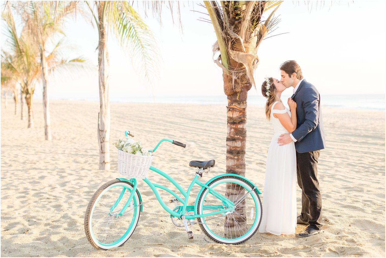 couple kissing by palm tree and teal bike