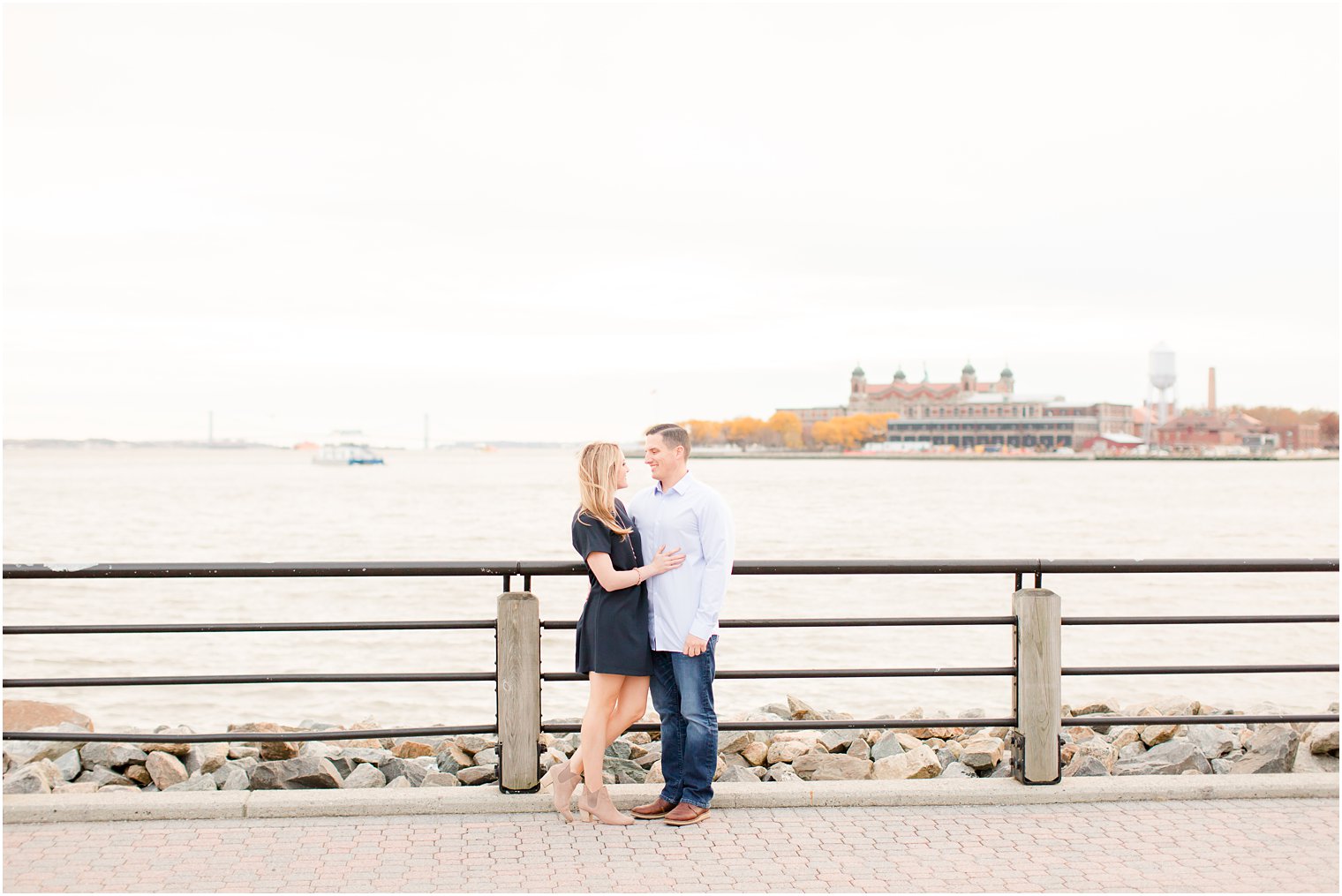 Engaged couple posing for photo in front of Ellis Island