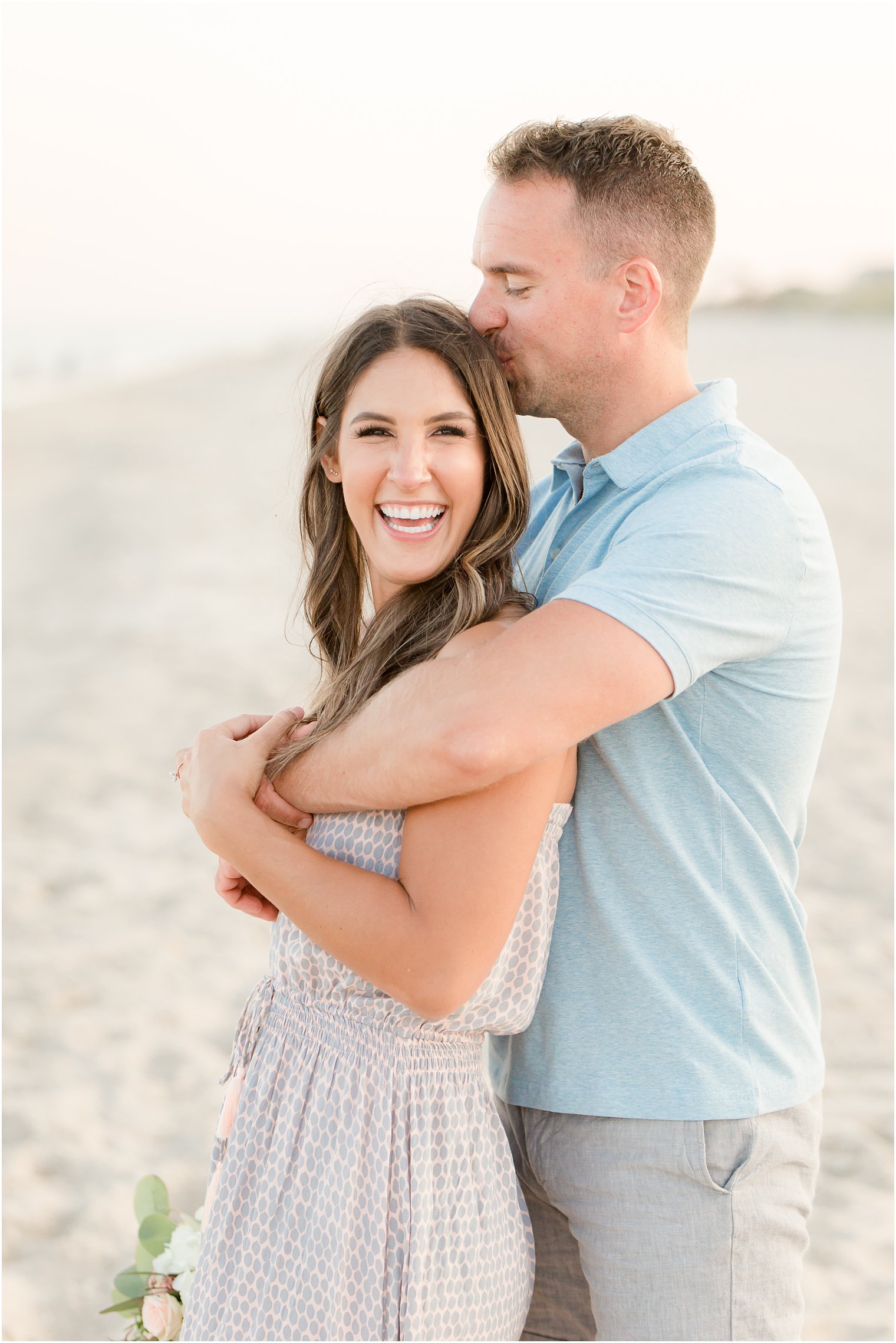 engaged couple holding each other on the beach