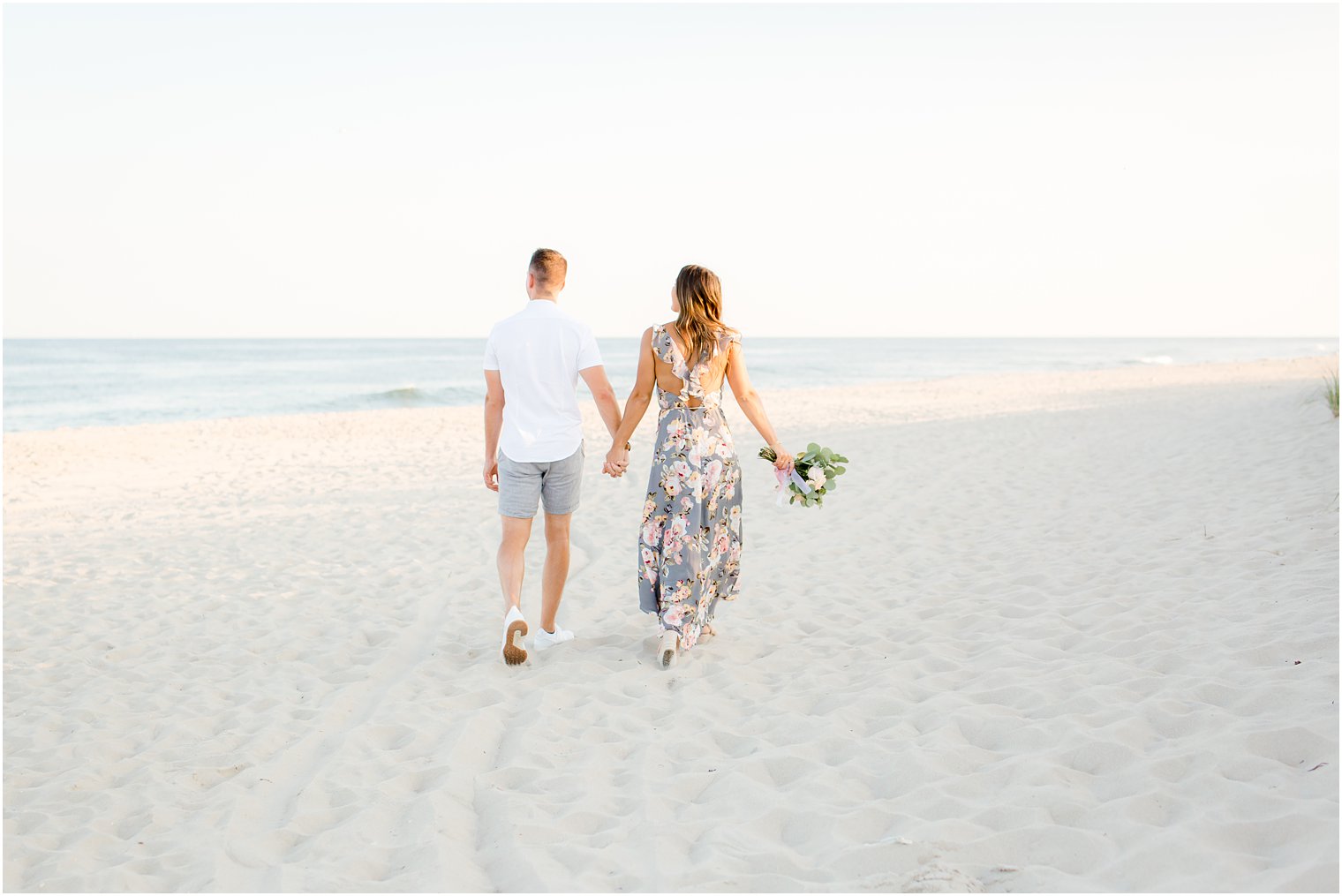 engaged couple walking on the beach holding hands on LBI
