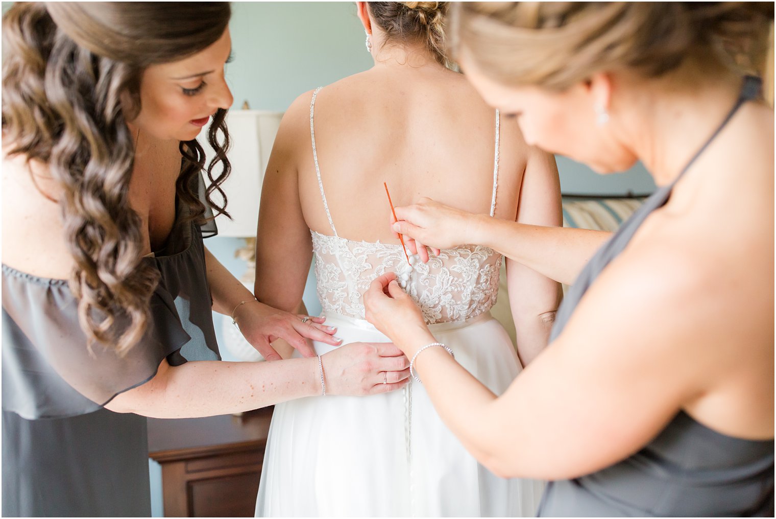Bridesmaids helping bride get into her wedding dress