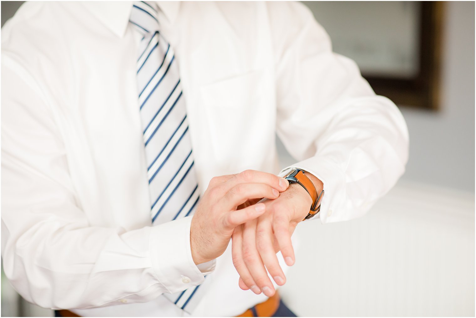 Groom putting on his watch on wedding day