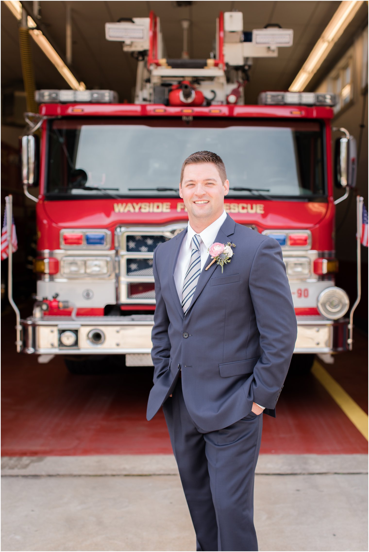 Groom posing for photos in front of firehouse