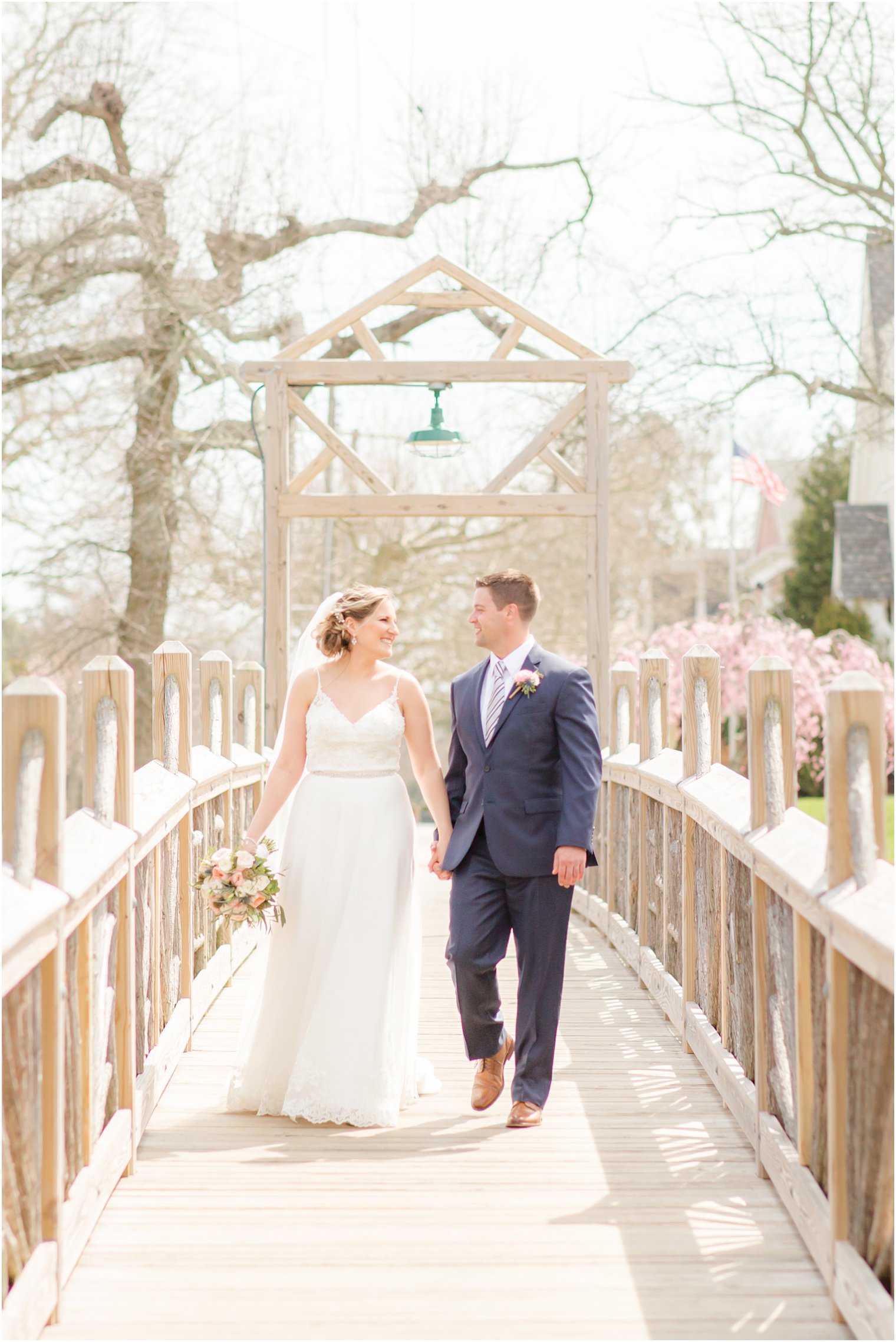 Bride and groom walking on a wooden bridge at Divine Park in Spring Lake 